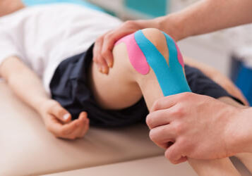 Physiotherapist doing with child exercise for knee